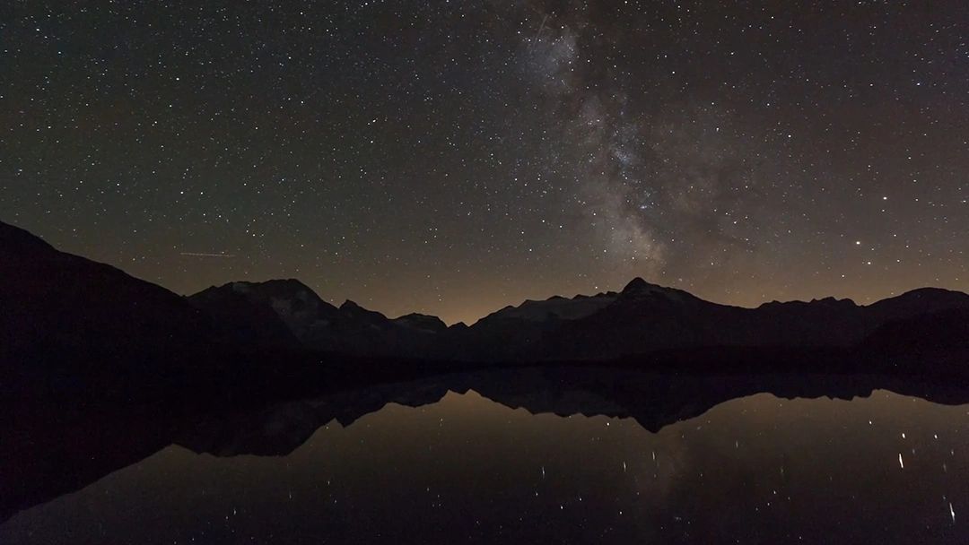 Night horizon and stars reflected over a mountain lake